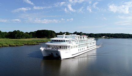 The American Eagle cruise ship sails along a quiet river.